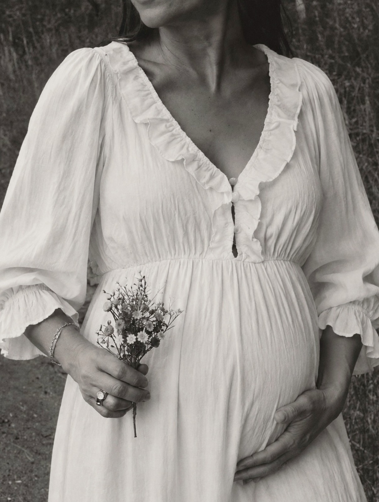 Retrato preto e branco de gestante com vestido branco e flores