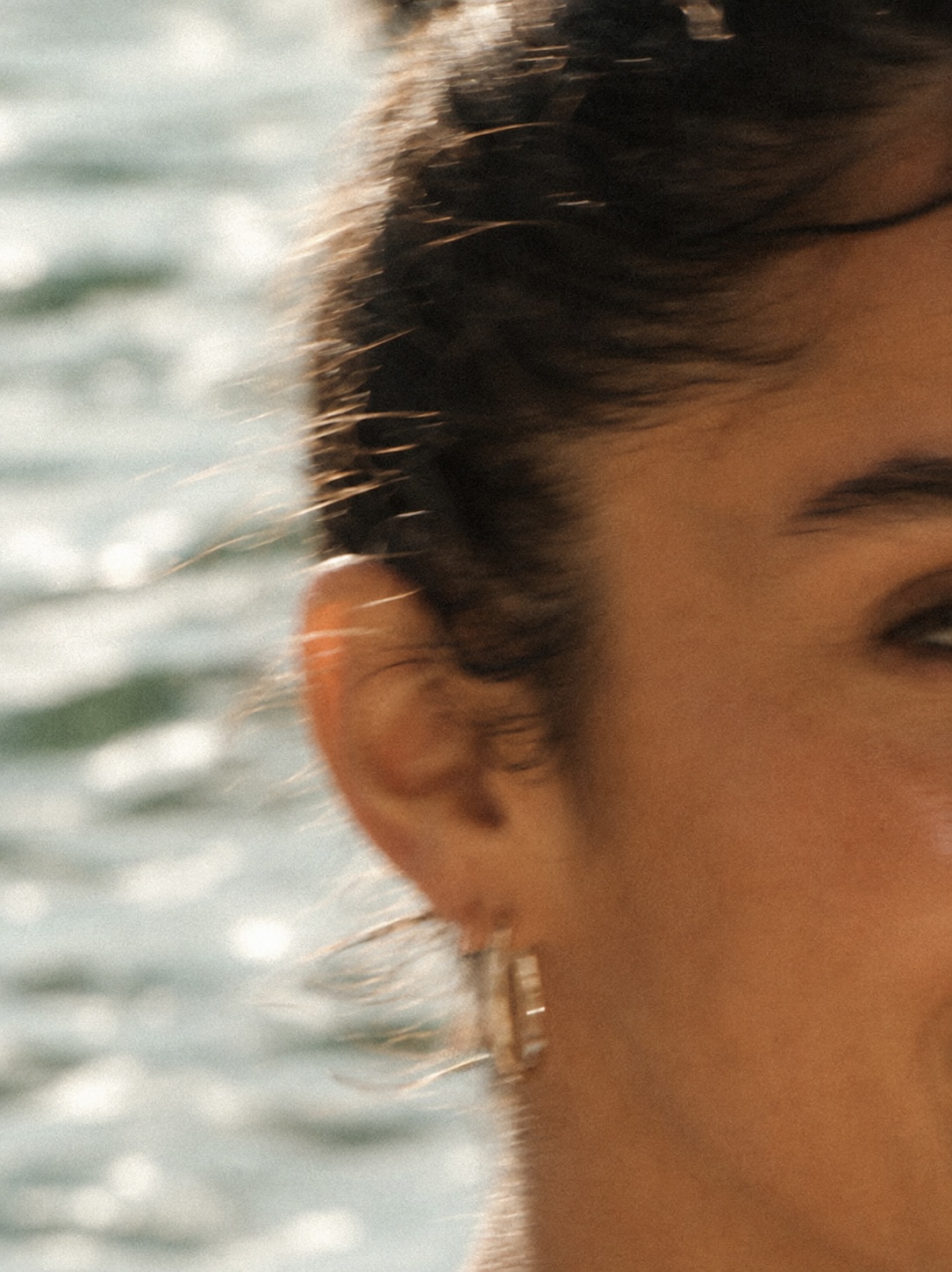 Detalhe do rosto e brinco de modelo junto ao mar