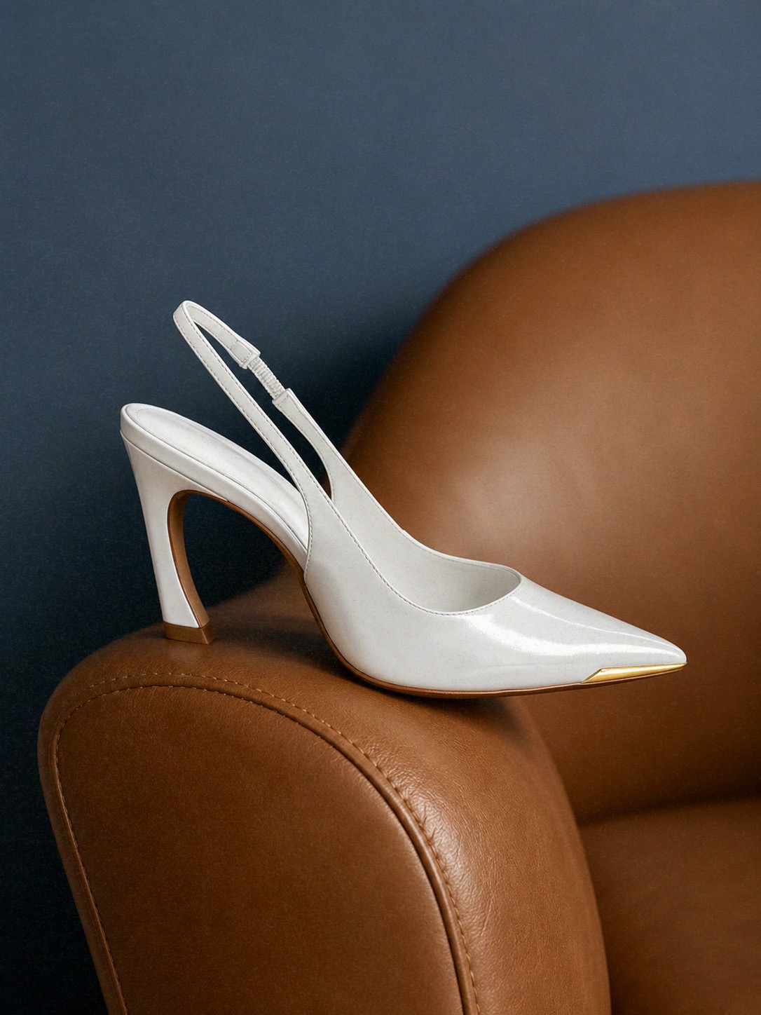Scarpin branco SCHUTZ sobre poltrona de couro