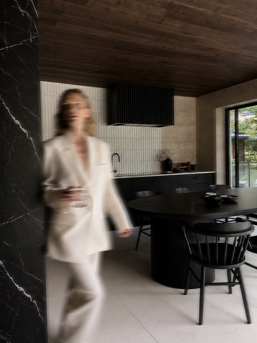 Pessoa atravessando uma cozinha residencial com um copo de água
