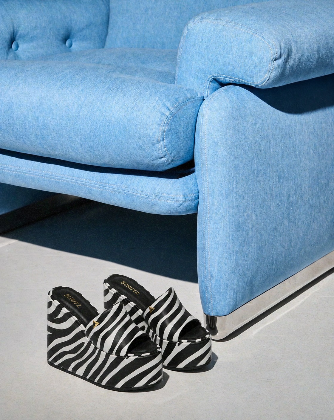 Plataformas listradas SCHUTZ diante de sofá azul
