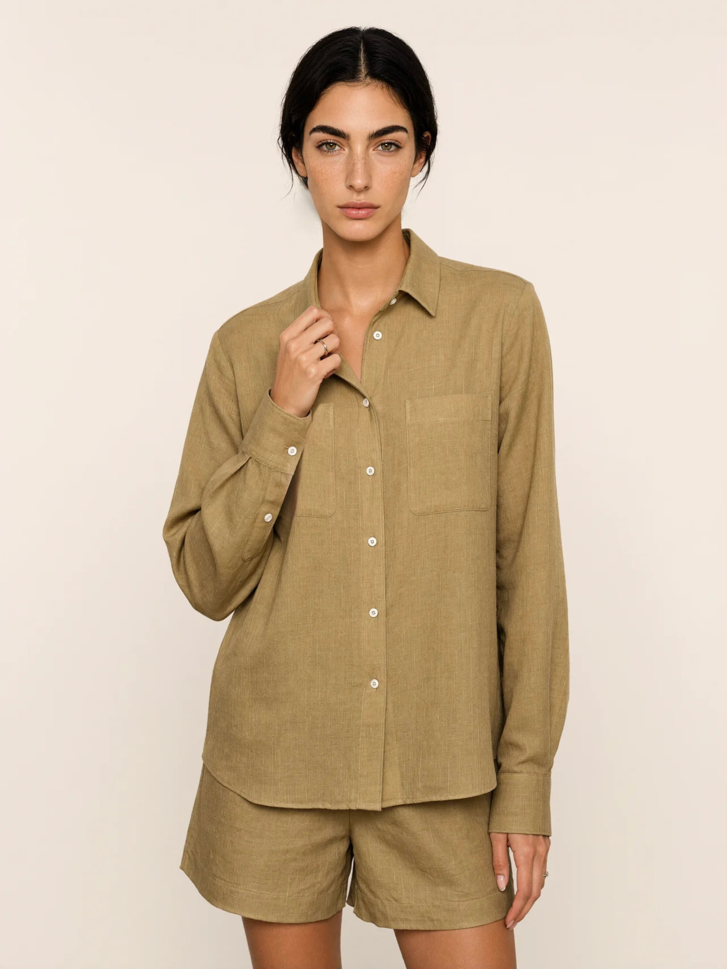 Modelo de frente com camisa e shorts em tom oliva